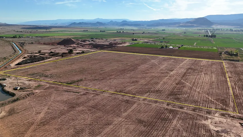 Expansive land parcel with distinct boundaries, surrounded by agricultural fields and distant mountain ranges
