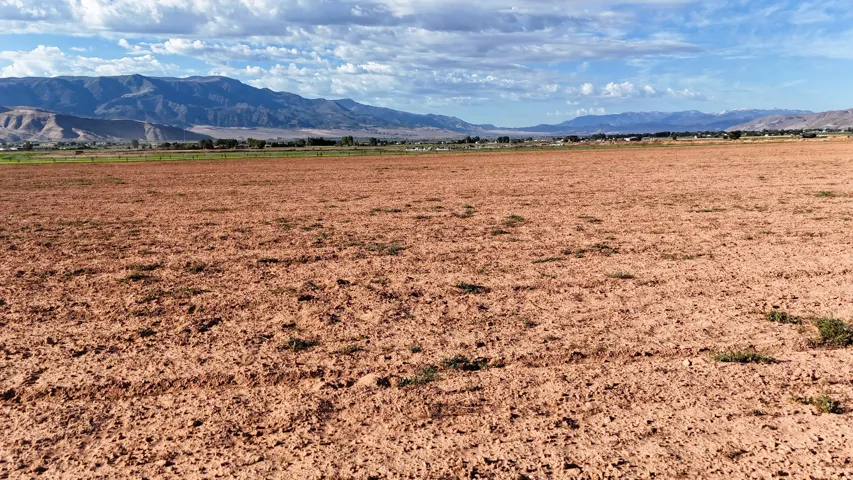Expansive open land with distant mountain ranges and a partially cloudy sky