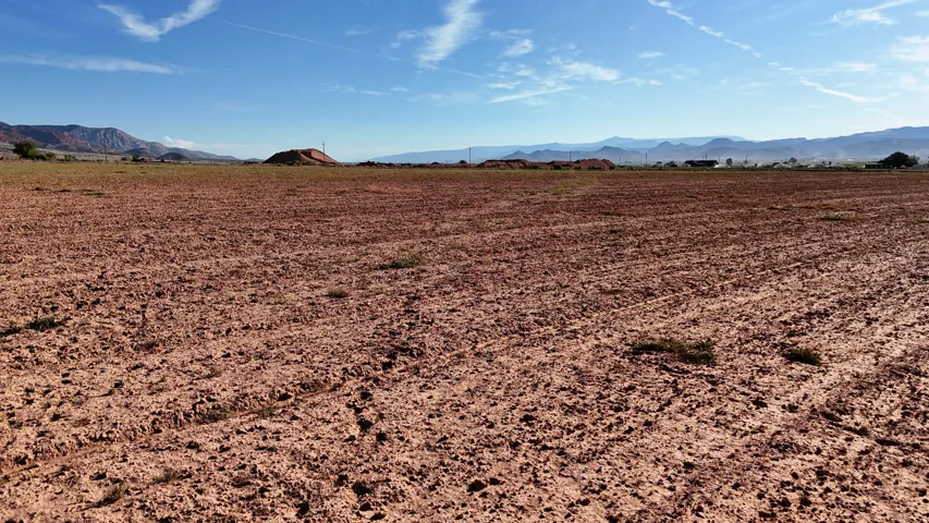 Expansive land parcel with reddish-brown soil and distant mountains