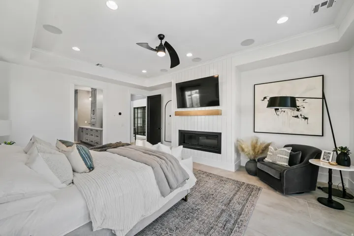 Recessed lighting, ceiling fan, shiplap accent wall, built-in fireplace, and tray ceiling