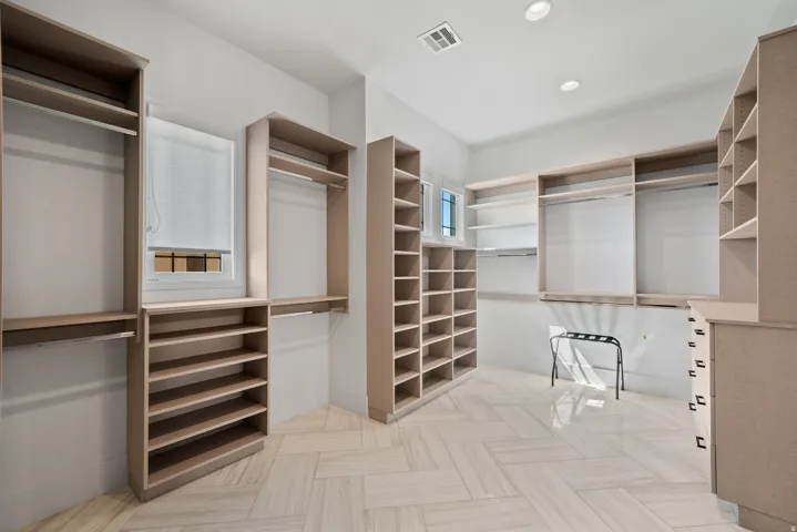 Expansive walk-in closet featuring extensive built-in shelving, hanging rods, integrated drawers, and a window for natural light