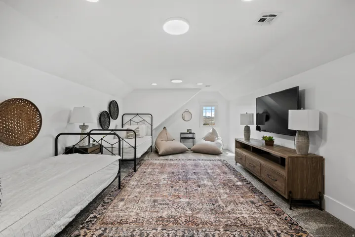 Sloped ceilings with recessed lighting, small window offering natural light, and wood-finish media console