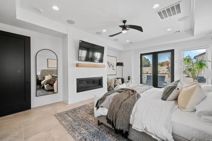 Recessed ceiling lighting, a contemporary linear fireplace with wood mantel, French doors leading to an outdoor area, a ceiling fan, and light-toned flooring
