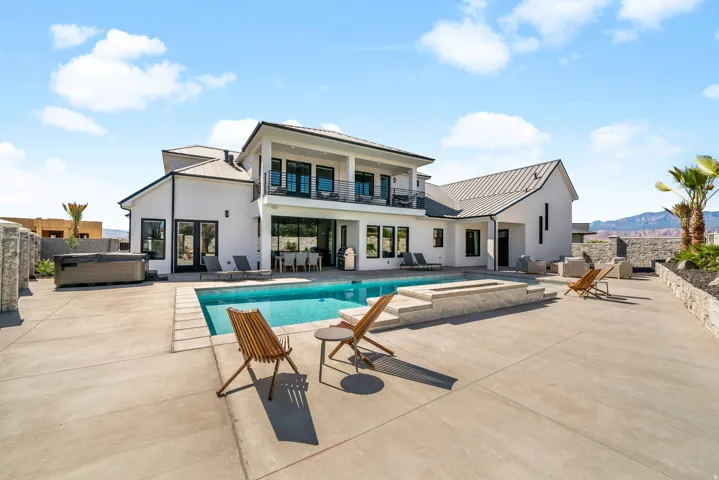Modern exterior with a white stucco finish, black-framed windows, a built-in swimming pool, a hot tub, and an integrated fire pit