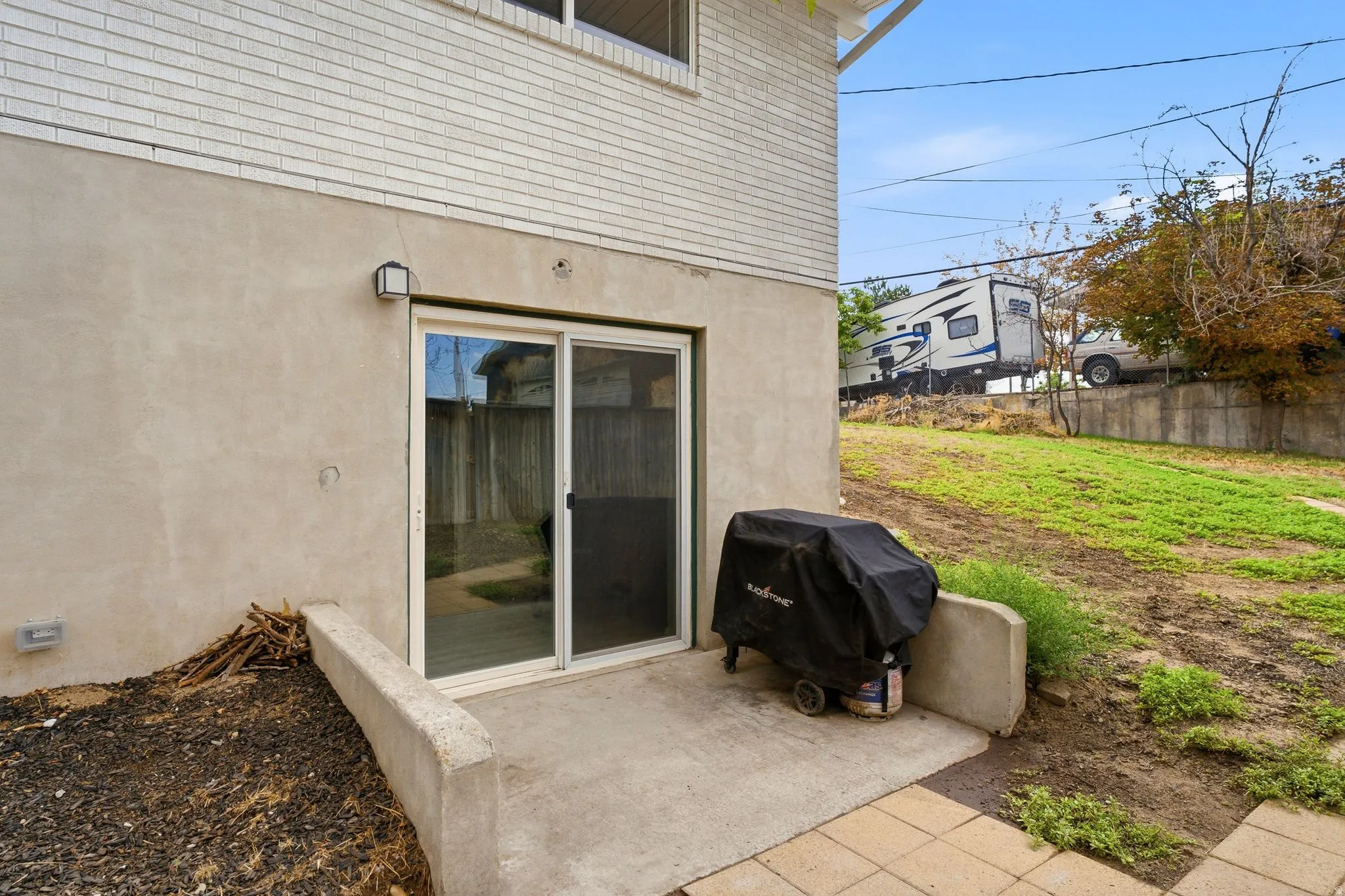 Ground-level entry with sliding glass door, white brick upper exterior, and stucco lower exterior