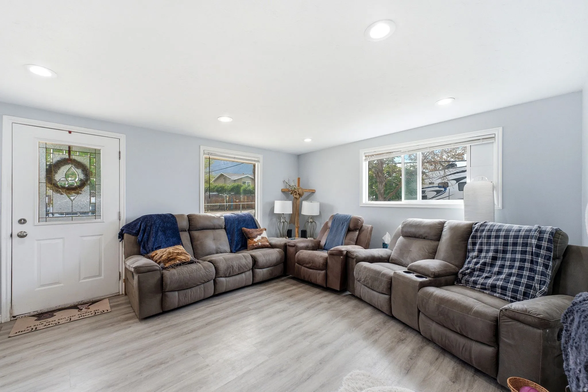 Recessed ceiling lighting, wood-finish flooring, light gray wall paint, and white trim windows