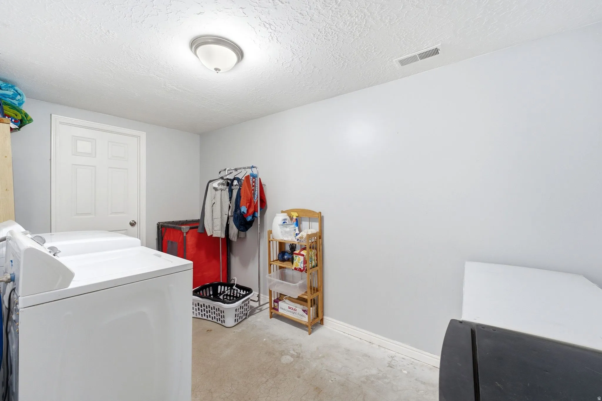 Laundry area with white walls and a white door