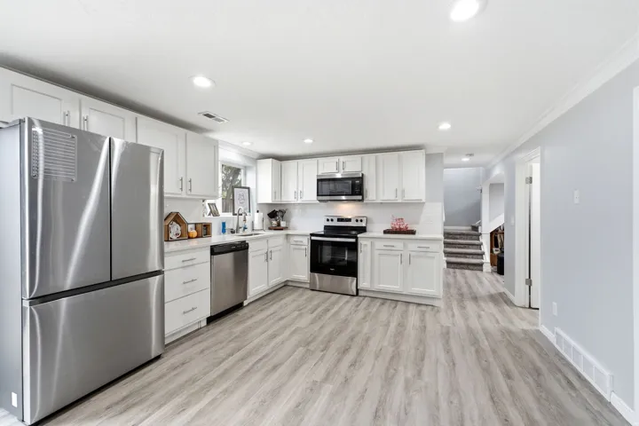 Kitchen featuring white cabinetry, stainless steel appliances, light-toned wood-finish flooring, and recessed lighting