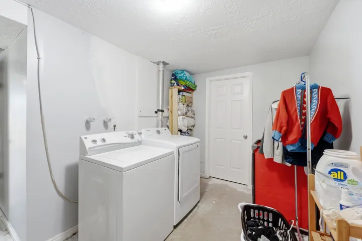 Dedicated laundry area featuring a washer and dryer, concrete flooring, and a paneled door