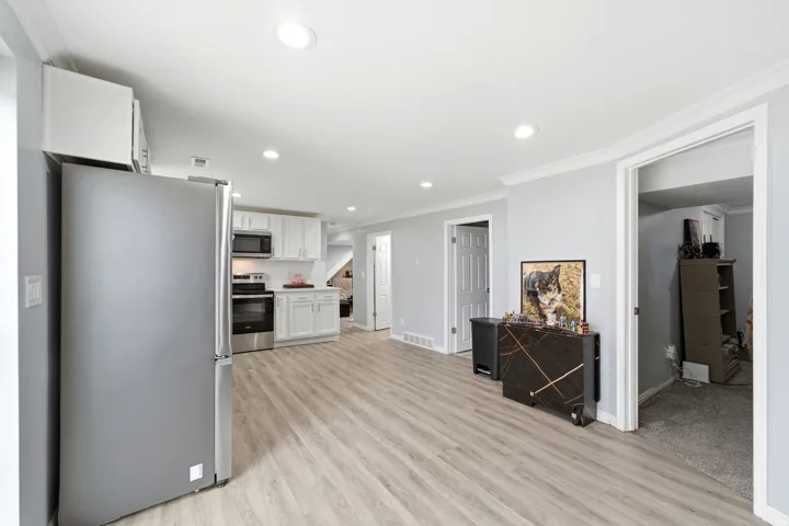 Modern kitchen with stainless steel appliances, white cabinetry, and wood-finish flooring
