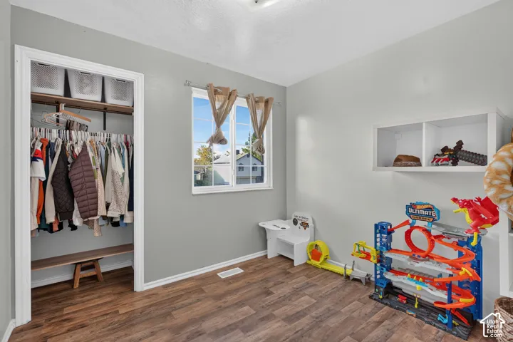 Wood-finish flooring with light gray walls, a built-in closet with shelving, and a white built-in wall shelf