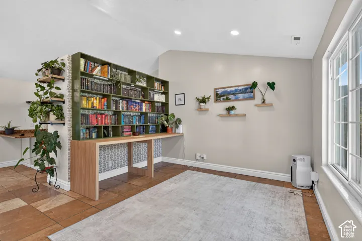Recessed lighting, built-in shelving, wood-finish desk, and tiled flooring