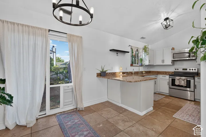 Kitchen featuring stainless steel appliances, white cabinetry, granite-style countertops, and tile flooring