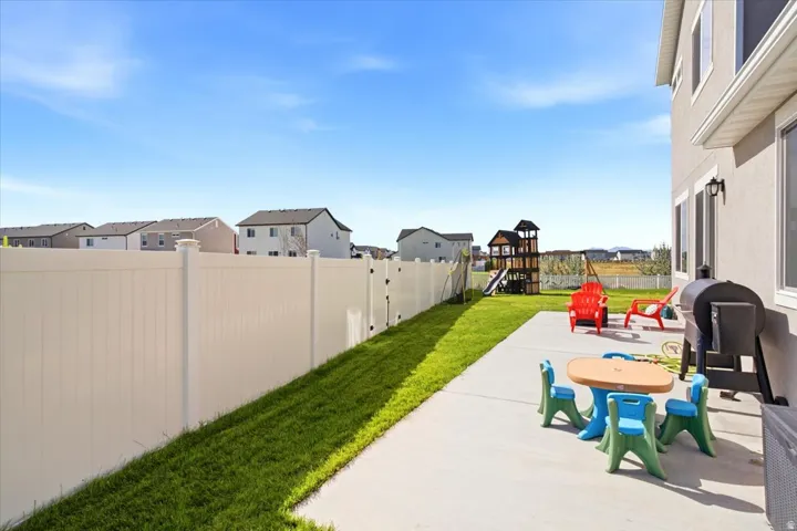 Expansive backyard featuring a concrete patio, a privacy fence, and a manicured lawn