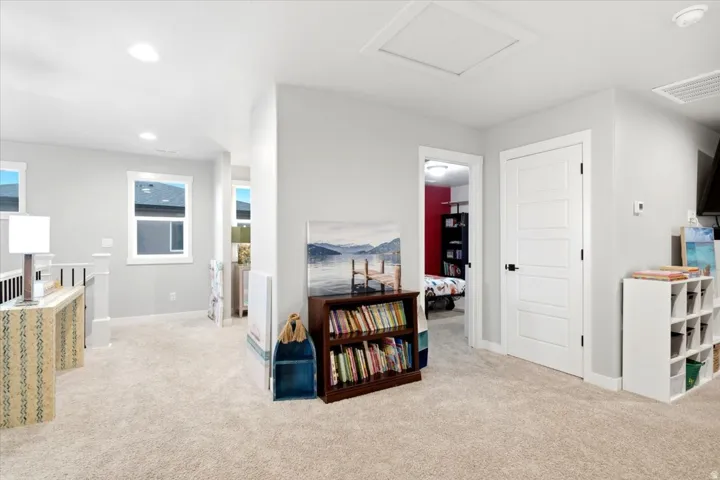 Carpeted hallway featuring white trim, flush-mounted ceiling lighting, and a five-panel interior door with matte black hardware