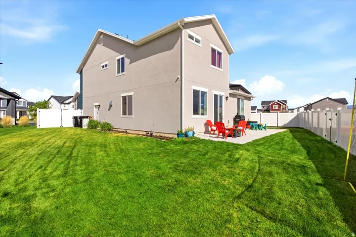 Rear exterior with stucco siding, a concrete patio, and a manicured lawn