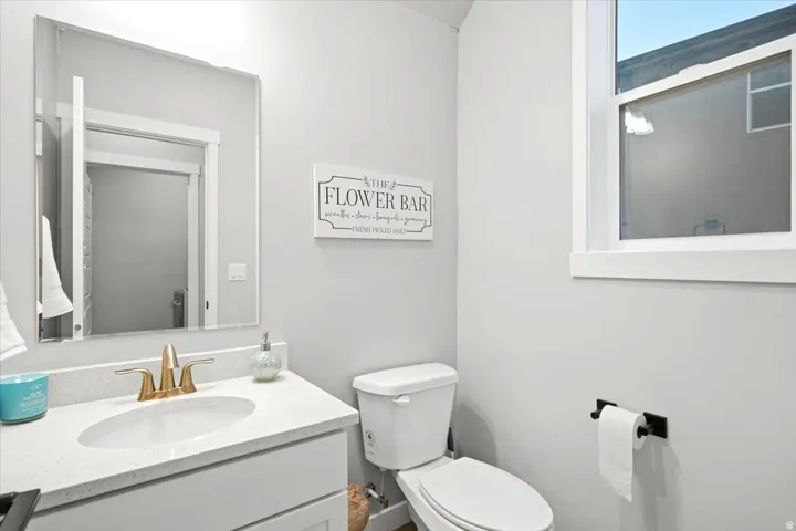 White vanity with a light-toned countertop, undermount sink, and brass-finish faucet