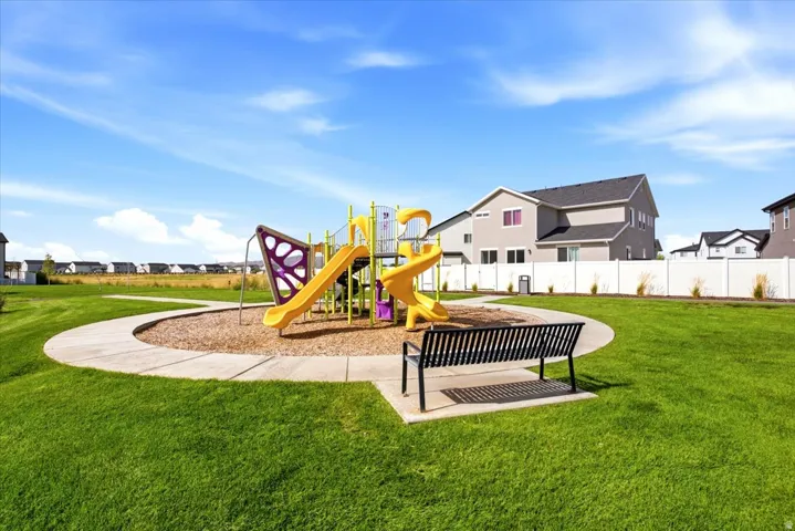 Community playground featuring a colorful play structure, integrated bench seating, and surrounding green space
