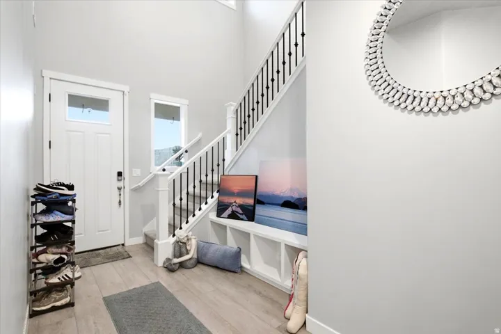 Two-story foyer with wood-finish flooring, white trim, and a staircase featuring black wrought iron balusters