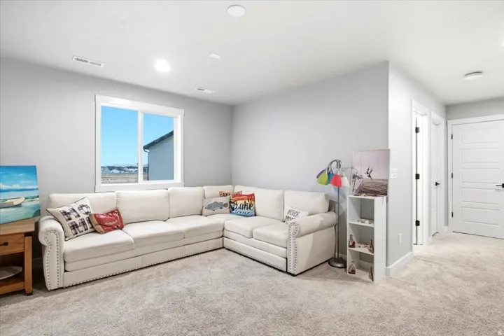 Recessed lighting, light gray wall paint, white trim, white paneled doors with black hardware, and gray carpeted flooring