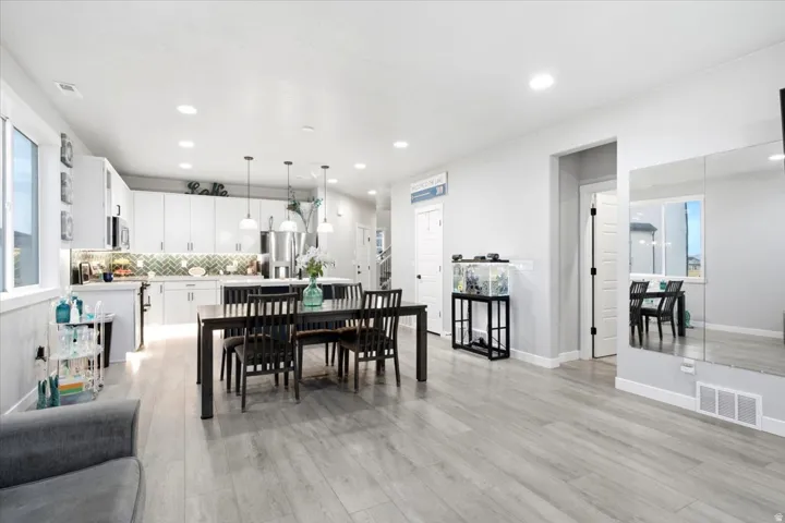 Open-concept living area with wood-finish flooring, recessed lighting, and large windows
