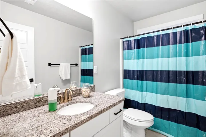 Bathroom featuring a vanity with a granite countertop, undermount sink, and a framed mirror