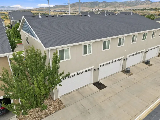 Modern townhome featuring a newly installed architectural shingle roof, stucco exterior with neutral finish, and three attached two-car garage bays with paneled doors