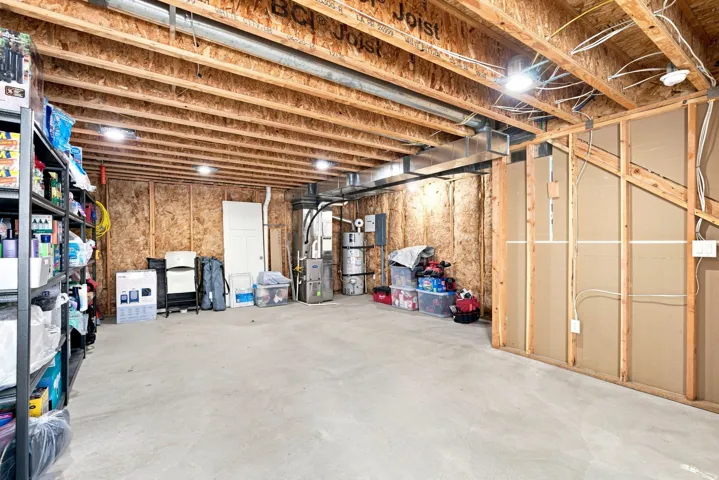 Unfinished basement with concrete flooring and exposed wood joists