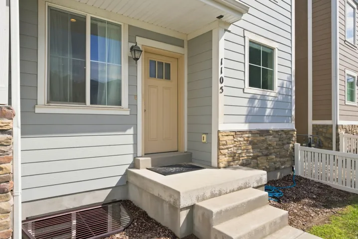 Light-toned siding exterior with stone accents and a white picket fence