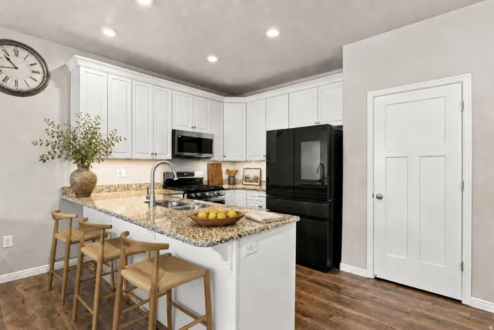 Kitchen featuring white cabinetry, granite countertops, wood-finish flooring, and recessed lighting