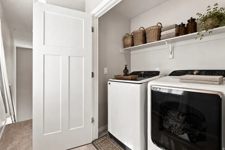 Dedicated laundry area featuring a full-size washer and dryer, integrated wall shelving, and neutral wall tones