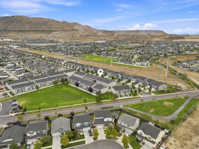 Expansive neighborhood showcasing a mix of single-family homes and townhomes, surrounded by open green spaces and a mountainous backdrop