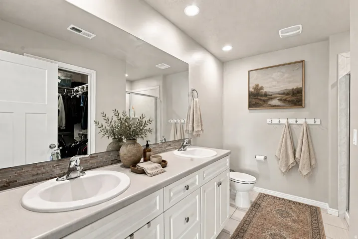 Dual vanity with integrated sinks, white cabinetry, and a full-width mirror