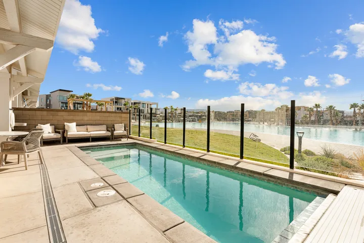 Private swimming pool with integrated spa, concrete paver decking, and a glass-paneled fence