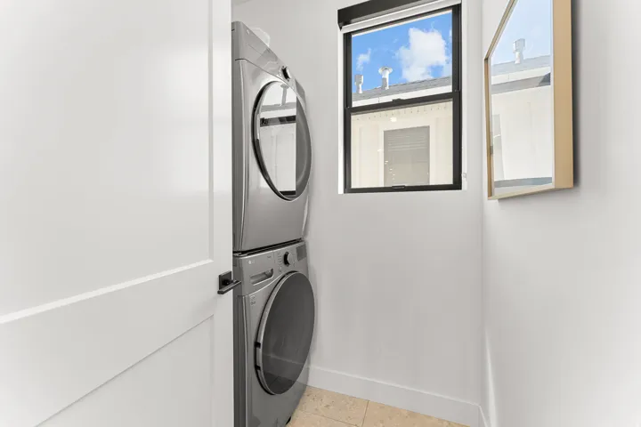 Stackable laundry appliances with a window, tile flooring, and a flat-panel interior door