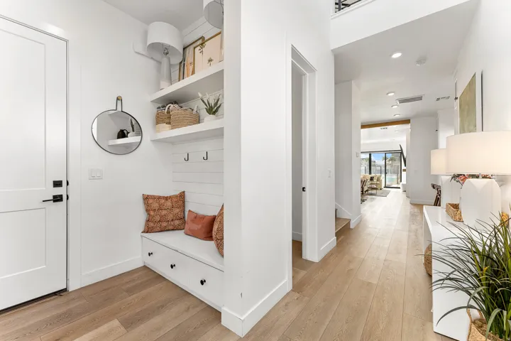 Entryway mudroom bench with built-in storage, white shiplap backing, and open shelving