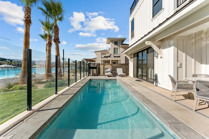 Private swimming pool with an adjacent patio, board and batten siding, and large sliding glass doors