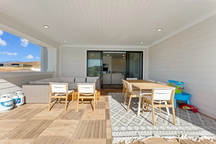 Covered outdoor patio with slatted wood-finish flooring, white shiplap walls, and recessed lighting