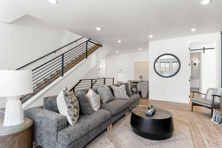 Open-concept living space with recessed lighting, wood-finish flooring, and a modern stair railing with horizontal balusters