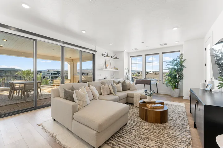 Bright living space with wood-finish flooring, recessed lighting, and large sliding glass doors leading to an outdoor balcony
