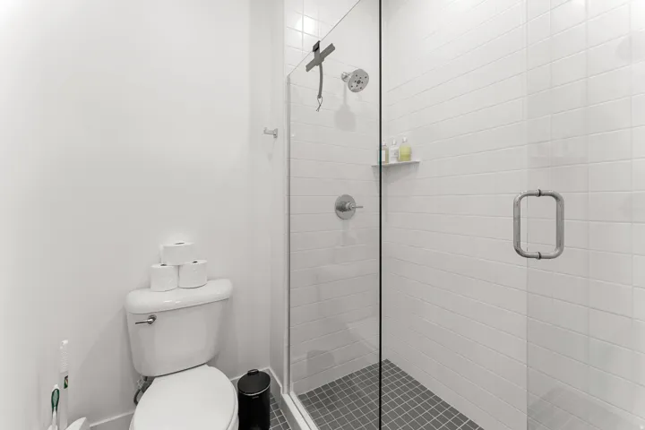 Glass-enclosed shower with subway tile surround, recessed shelf, and mosaic tile flooring