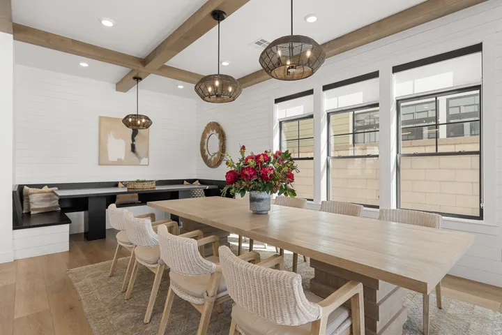 Exposed wood beams accentuating the ceiling, shiplap wall treatment, built-in banquette seating, wood-finish flooring, and multiple windows with black trim