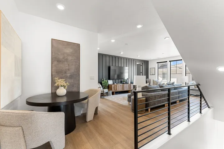 Recessed lighting throughout, wood-finish flooring, black horizontal bar railing, and large windows with black frames