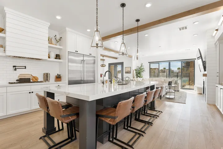 Spacious kitchen with a large island, white shaker cabinetry, stainless steel appliances, and light wood-finish flooring