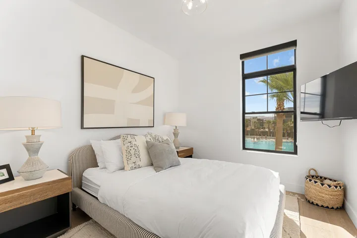Crisp white walls, large window with black framing, durable wood-finish flooring, and a contemporary ceiling light fixture