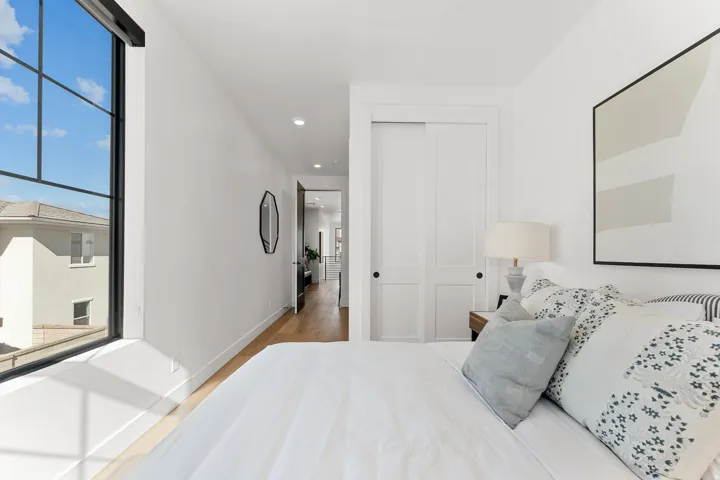 Expansive window with black grid panes, recessed ceiling lighting, wood-finish flooring, and white two-panel sliding closet doors