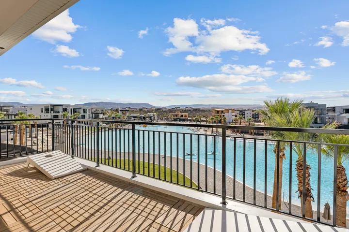 Expansive deck with wood-finish flooring, black wrought-iron railing, and palm tree accents