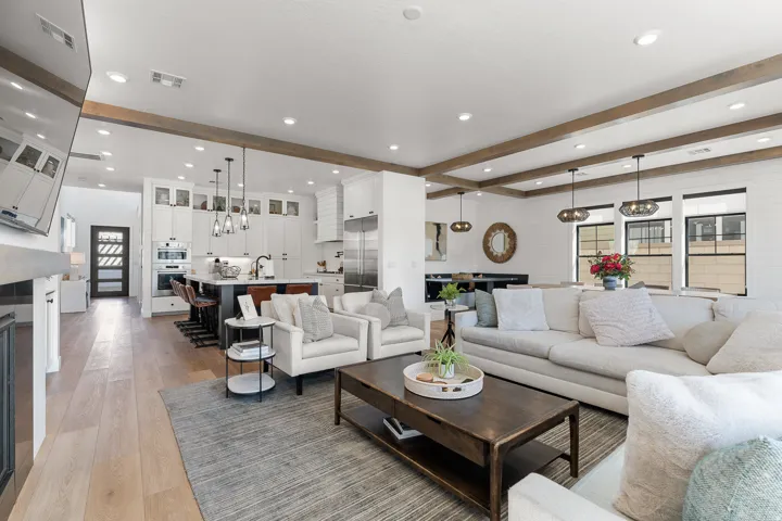 Open-concept living space with exposed wood beams, wood-finish flooring, and recessed lighting