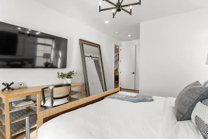 Modern black chandelier, recessed lighting, and a white paneled door with black hardware