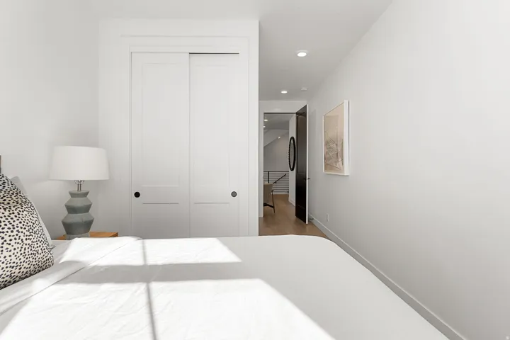 White sliding panel closet doors with black hardware, recessed ceiling lighting, and wood-finish flooring